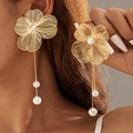 Dettaglio macro di orecchini a fiore dorato spazzolato con nappe di perle e petali - Orecchini a goccia con fiori cavi dorati