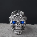 Macro detail of gothic skull ring with blue crystal eyes on a textured stone base - Blue Eye Skull