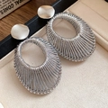 Silver oval woven earrings with metallic texture displayed on a jewelry tray - Silver