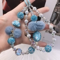 Detail of blue beaded phone strap with fuzzy pom-poms and crystal charms - Blue Floral