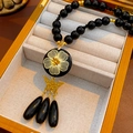 Detail of vintage necklace with black beads, gold flower pendant, butterfly and teardrops - Necklace-Gold-Black