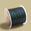 Macro view of strong and stretchy dark green elastic jewelry cord on a white plastic spool - Dark Green