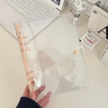 Detail of A6 transparent PVC 6-ring binder with pastel pink clips on an aesthetic desk - A5 / Turmeric