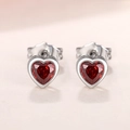 Macro shot of silver heart earrings with faceted red gemstones and secure butterfly backs - Red