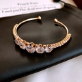 Golden open bangle with five large zircon stones and pave-set accents on black leather - Style 21 / Gold
