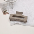 Macro detail of large matte coffee-colored claw clip with non-slip teeth on glass base - Cube / Grey Brown