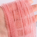 DIY accessory of 2mm and 3mm small pink natural agate round beads held by hand - Watermelon red