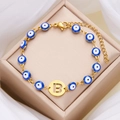 Bracciale in acciaio dorato con malocchio, ciondolo lettera B e perla blu - Lettera B