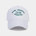 Detailed close-up of dark green embroidery on a white cotton baseball cap - Adjustable / White
