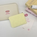 Makroaufnahme einer hellgelben gesteppten Münztasche mit Reißverschluss und Griff - Gelb