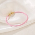 Pink woven mesh bracelet with gold cylindrical ends on elegant white silk fabric - Light Pink