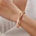 Elegant twisted bangle featuring gold-tone metal and pink marble resin inlay on wrist - Gold with Pale Pink Marble Style