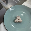 Cute beige bear-shaped hair claw clip with heart cutouts on a blue ceramic plate - Khaki