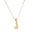 Detailed close-up of golden letter J pendant with dotted texture on a fine metal chain - Letter J