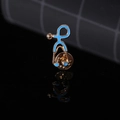 Macro shot of blue enamel stethoscope brooch with gold metal plating on reflective base - Blue