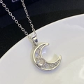 Macro shot of S925 silver moon pendant with sparkling white diamonds on a white surface - Silver (8306)