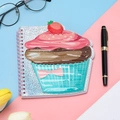 Macro shot of a cupcake-shaped notebook with pink metal spiral and glittery cover - Cake