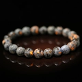 Grey flame stone beaded bracelet with vibrant orange spots on a black reflective surface - Dark Grey / Fluorescent Orange