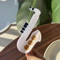 Détail d'une pince à cheveux saxophone en acétate blanc avec des touches dorées - Saxophone Blanc
