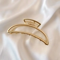 Macro detail of a matte gold crescent hair claw clip on white silk background - Large Moon