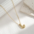 Minimalist gold necklace with puffy letter J pendant on a white textured background - Letter J