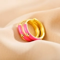 Macro view of pink enamel gold-plated hoop earrings with micro-set cubic zirconia stones - Pink