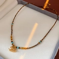 Detailed macro view of vintage beaded tiger eye necklace with golden rocking horse pendant - Necklace - Gold Horse Pendant