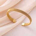 Elegant gold mesh stainless steel open cuff bracelet on soft beige velvet background - Gold