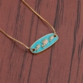 Detailed macro view of gold chain bracelet with turquoise elephant pendant on wood surface - Turquoise Elephant