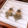 Makro-Detail von Vintage-Ohrringen mit blauen Edelsteinen und grauen Kristallquasten - Gold