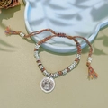 Close-up of a colorful woven ethnic bracelet with a silver pendant and tassels on a tray - Colored Rope Silver Spacers Bracelet: God of Wealth