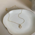 Elegante collana d'oro con ciondolo rotondo in perla bianca e diamanti su vassoio ceramica - Perla Rotonda