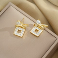 Golden bowknot cubic zirconia earrings displayed elegantly on a beige jewelry box lid - Bowknot Square Stud Earrings (361)