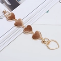 Detailed shot of gold metal phone chain with four brown velvet heart shaped pendants - Khaki