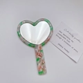 Detailansicht herzförmiger Acetatspeigel mit rosa-grünem Marmormuster für Damen - Grün - Herzblumenmuster