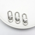 Detailed view of three silver swivel snap hooks with round keyrings on a white plate - White K U-Shaped Hook Clasp / Silver