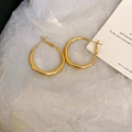 Detailed view of irregular golden hoop earrings on a minimalist white paper backdrop - Silver Needle Gold Small