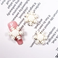 Macro-opname van witte sneeuwvlok hars bedeltjes op roze nagels voor kerstkunst - #301