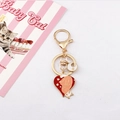 Detail eines goldenen Katzen-Schlüsselanhängers mit einem roten Herzanhänger und Katze - Herz-Katze