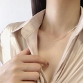 Close-up of elegant gold snake bone chain necklace on model wearing silk blouse - Gold Round Snake Chain