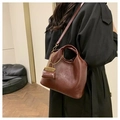 Detalle de bolso tote de cuero encerado marrón oscuro con estuche y cadena de metal en modelo - Burdeos