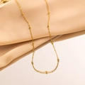 Elegante 18K vergulde kralenketting gepresenteerd op zachte beige zijden stof - Parelketting / Goud