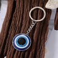 Close-up of a blue Evil Eye keychain with silver link chain on rustic tree bark background - 2 25MM Silver Eye