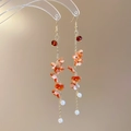 Detailed view of orange resin floral earrings with pearl tassels on a clear acrylic stand - Hook Style - Orange Brown Floral Pearl Tassel