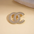 Close-up of interlocking gold brooch with geometric crystals and vintage pearl details - Gold C Shape