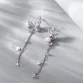 Eleganti orecchini a farfalla con perle e nappe lunghe su sfondo grigio chiaro neutro - Argento