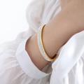 Eleganter vergoldeter Armreif mit vollflächigem Zirkonia-Besatz auf weißem Chiffon - Gold