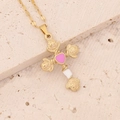 Détail du pendentif croix rose dorée avec cœur rose sur une surface en pierre - Rose Rouge