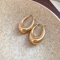 Macro shot of chunky gold oval hoop earrings with a mirror polished metal finish - Gold Chunky Hoop
