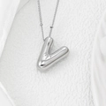 Detailed macro view of a 3D polished silver V-letter pendant on a delicate chain necklace - Letter V Pendant